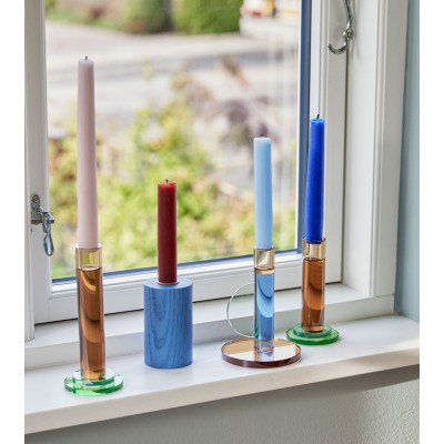 Ensemble de bougeoirs colorés sur un rebord de fenêtre.