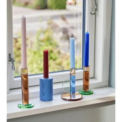 Ensemble de bougeoirs colorés sur un rebord de fenêtre.