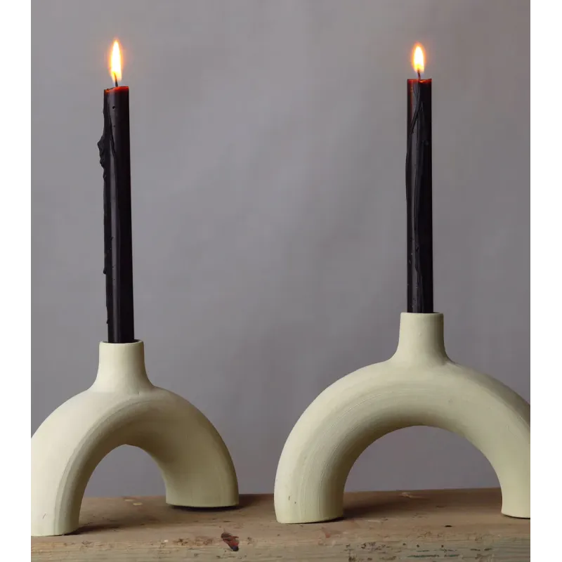 Bougeoir arc en céramique brute avec chandelles noires, style minimaliste.