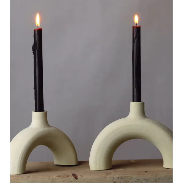 Bougeoir arc en céramique brute avec chandelles noires, style minimaliste.