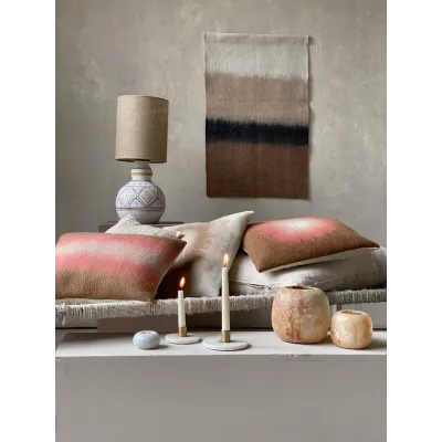 Ambiance salon avec coussins et bougeoirs en marbre, pour un style élégant et accueillant.