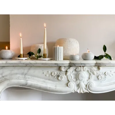 Bougeoirs en marbre allumés, disposés sur une cheminée décorative.