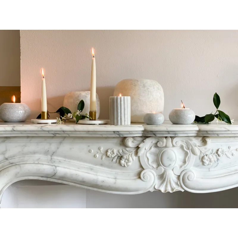 Bougeoirs en marbre allumés, disposés sur une cheminée décorative.