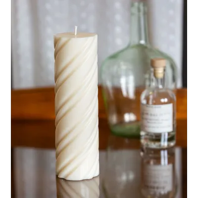 Bougie naturelle et artisanale en cire de colza Ø 7 cm H 23 cm sur une table en verre