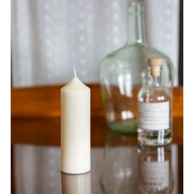 Bougie artisanale en cire naturelle de colza Ø 5 cm H 14 cm posée sur une table en verre