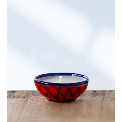 Bougie parfumée dans une coupe rouge et bleu aux motifs élégants.