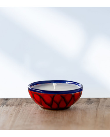 Bougie parfumée dans une coupe rouge et bleu aux motifs élégants.