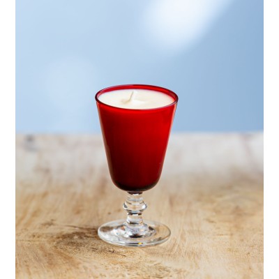 Bougie parfumée dans un verre à pied rouge élégant.
