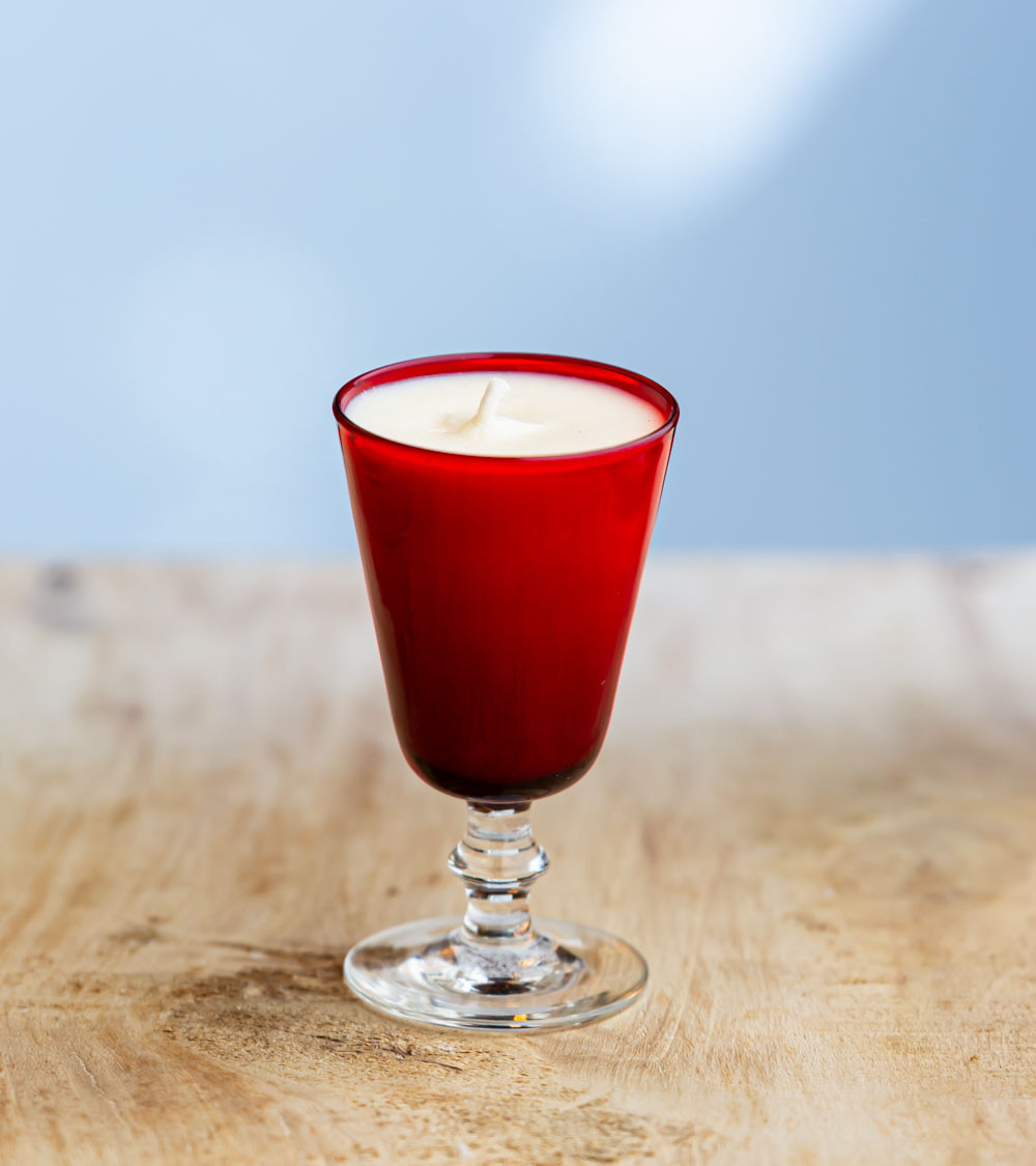 Bougie parfumée dans un verre à pied rouge élégant.