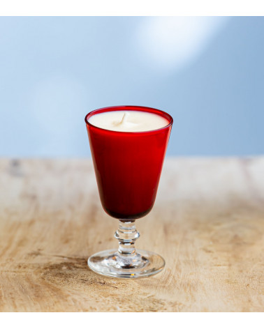 Bougie parfumée dans un verre à pied rouge élégant.